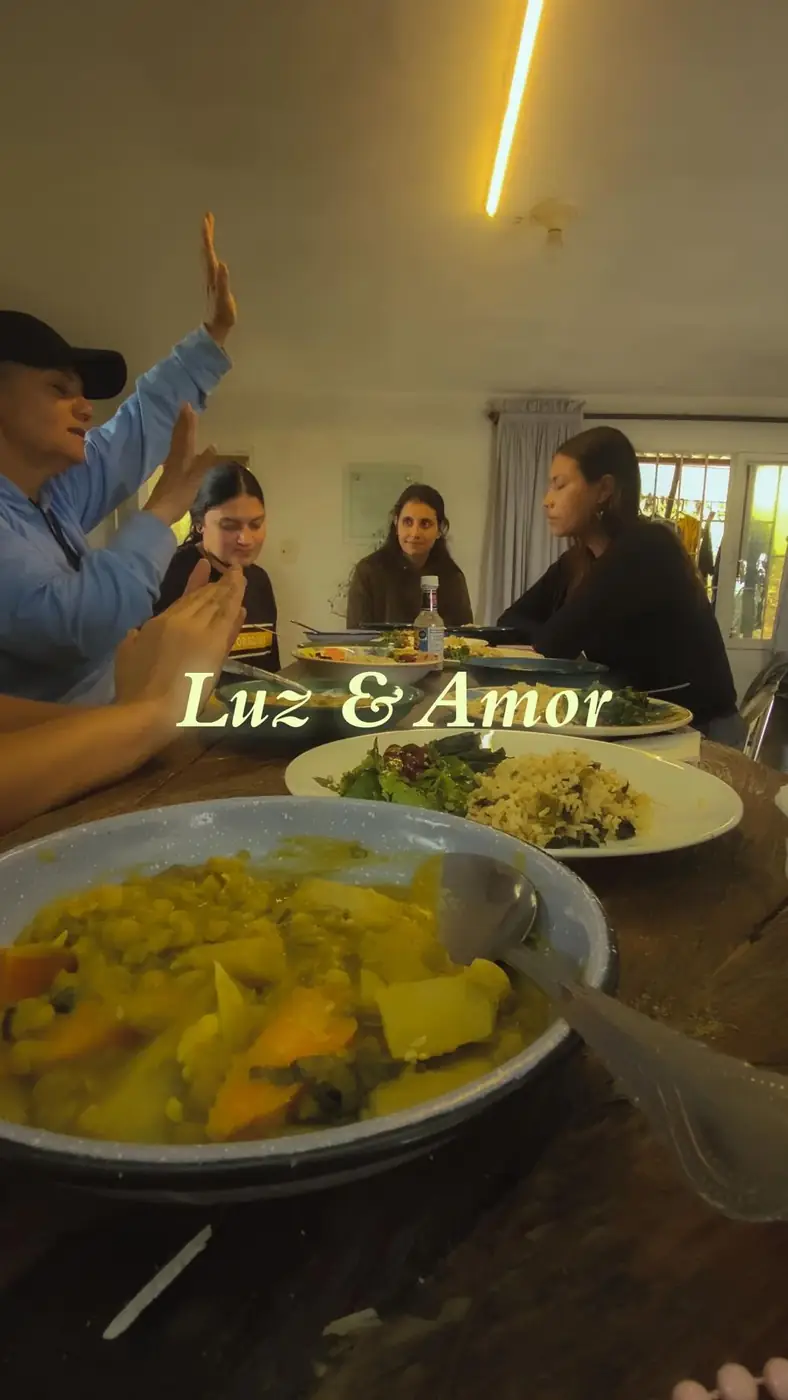 Mesa compartida con sopa, arroz y ensalada mientras las personas agradecen