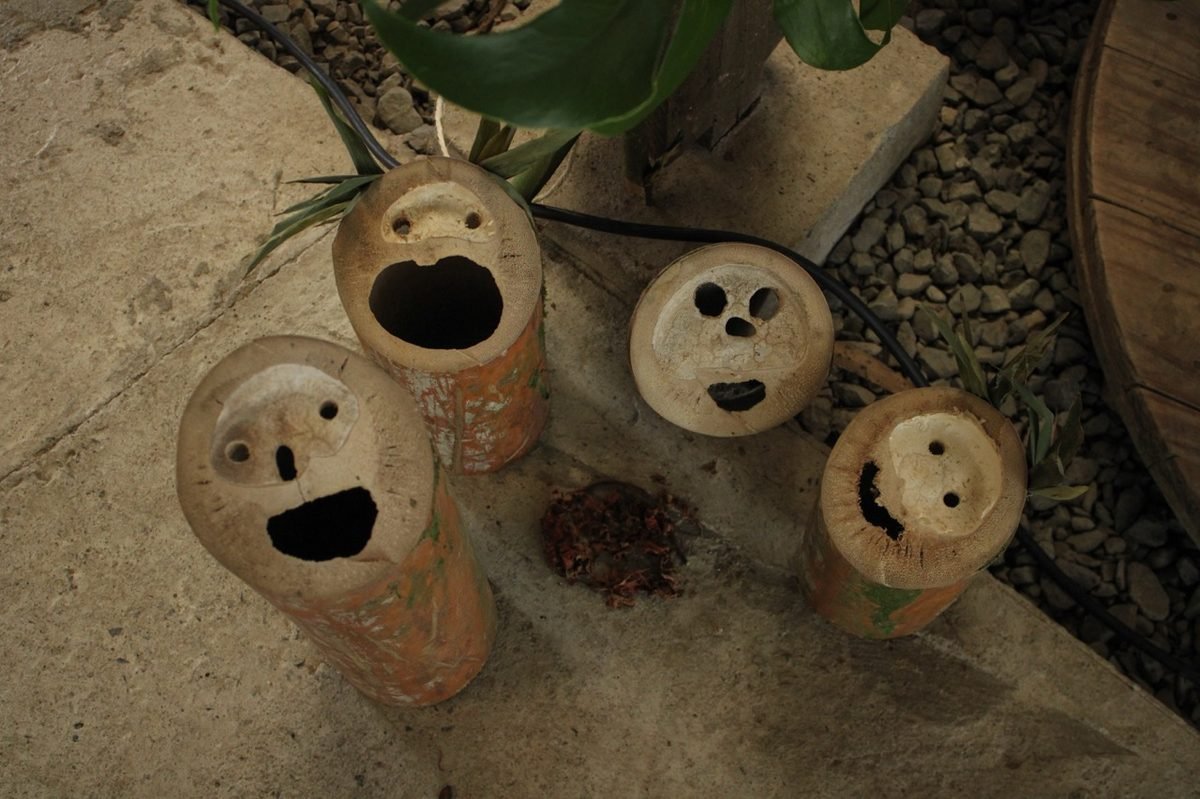 Trozos de bambu tallados con forma de rostros, usados como macetas decorativas