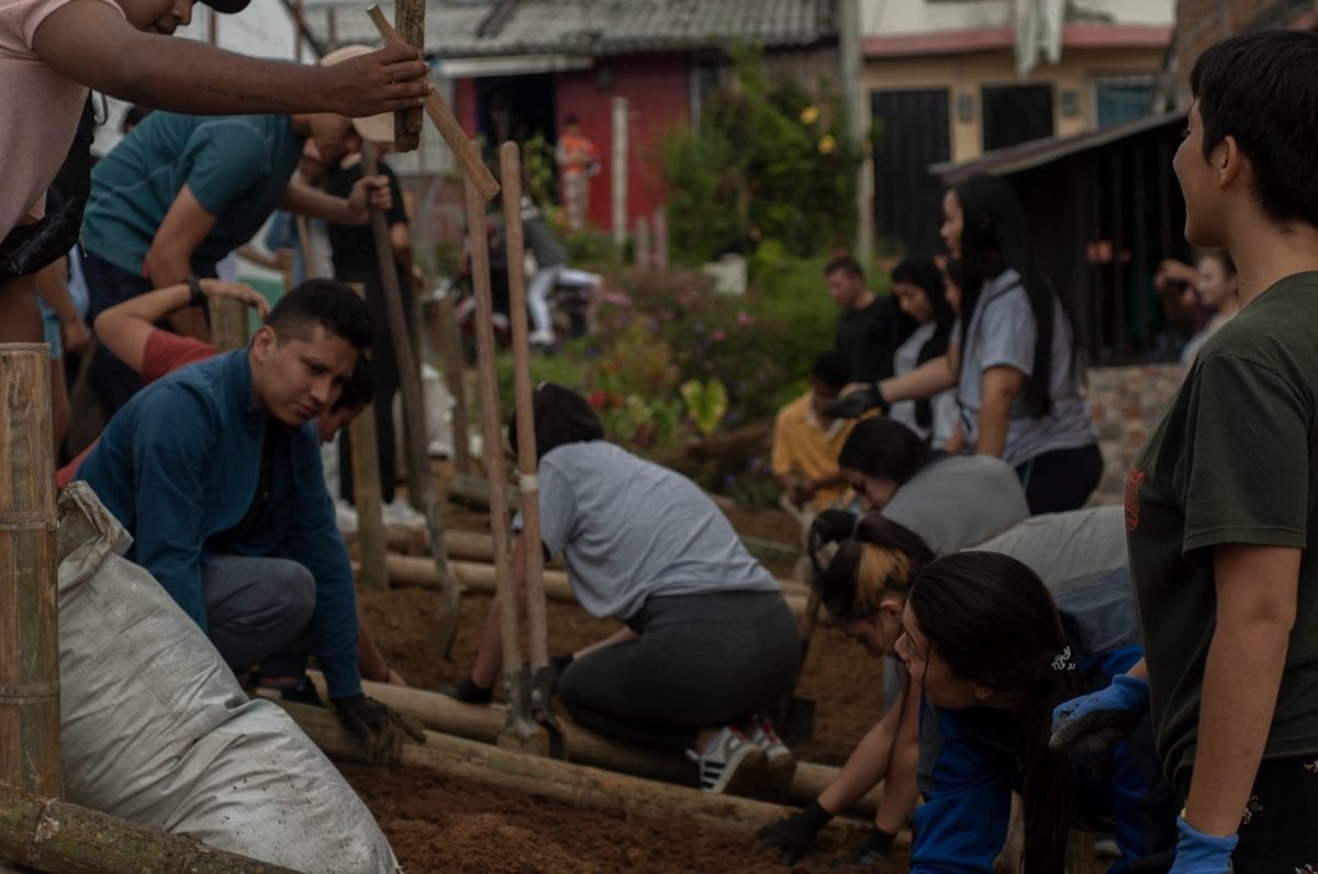 Voluntarios y comunidad trabajando en la construccion de camas de cultivo en madera